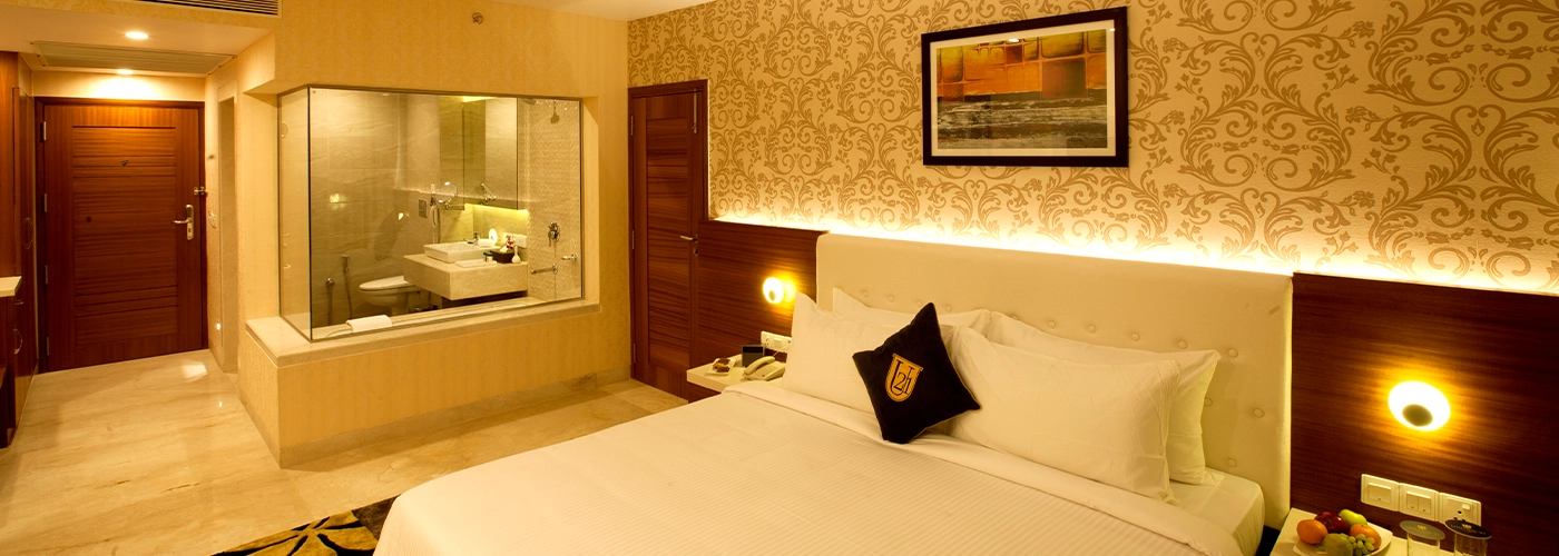 Luxurious hotel room with a king-sized bed, elegant wallpaper, and a glass partition bathroom